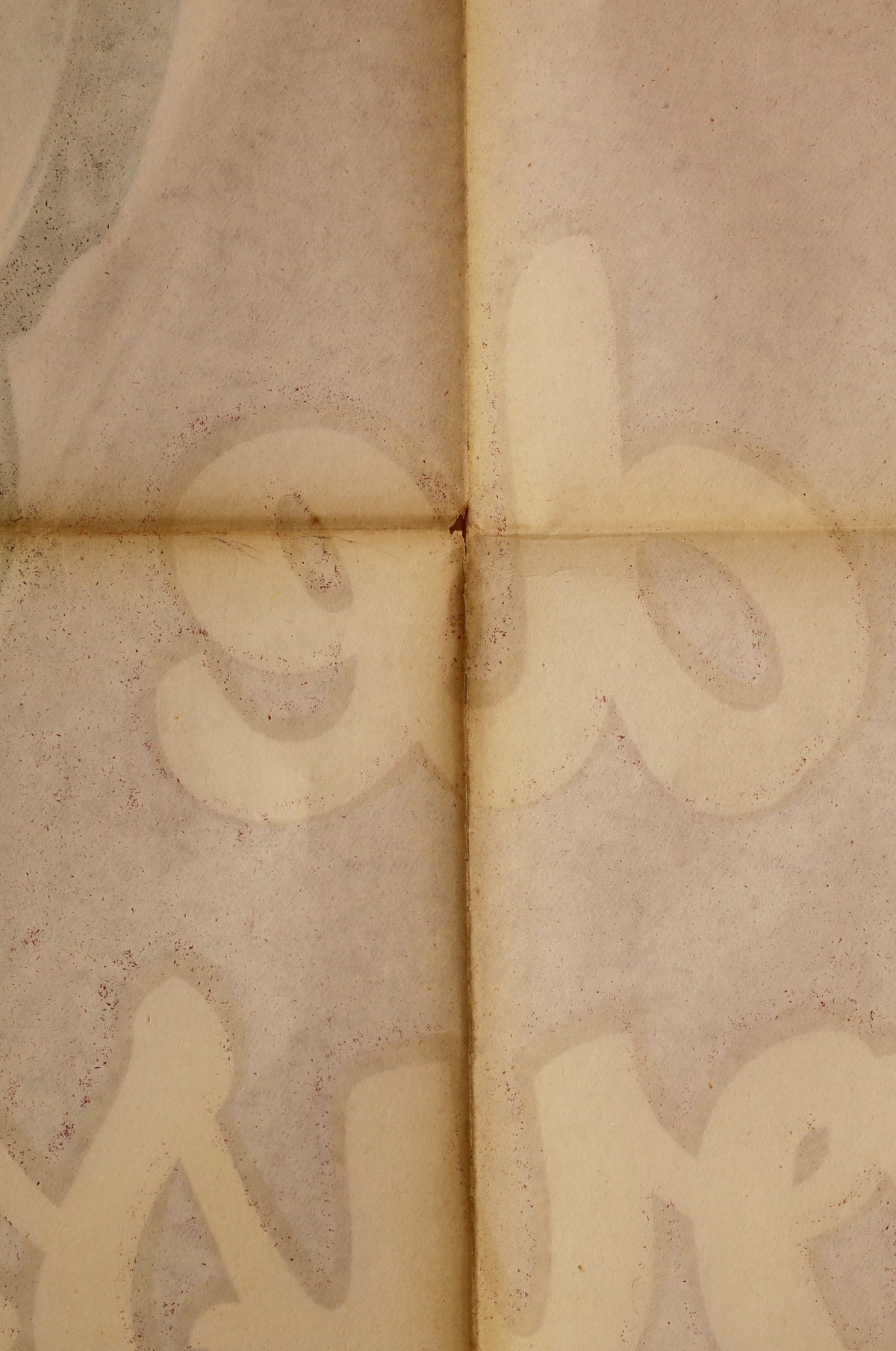 Close-up of the reverse showing fold lines, age toning, surface spotting, and faint bleed-through from the front artwork.