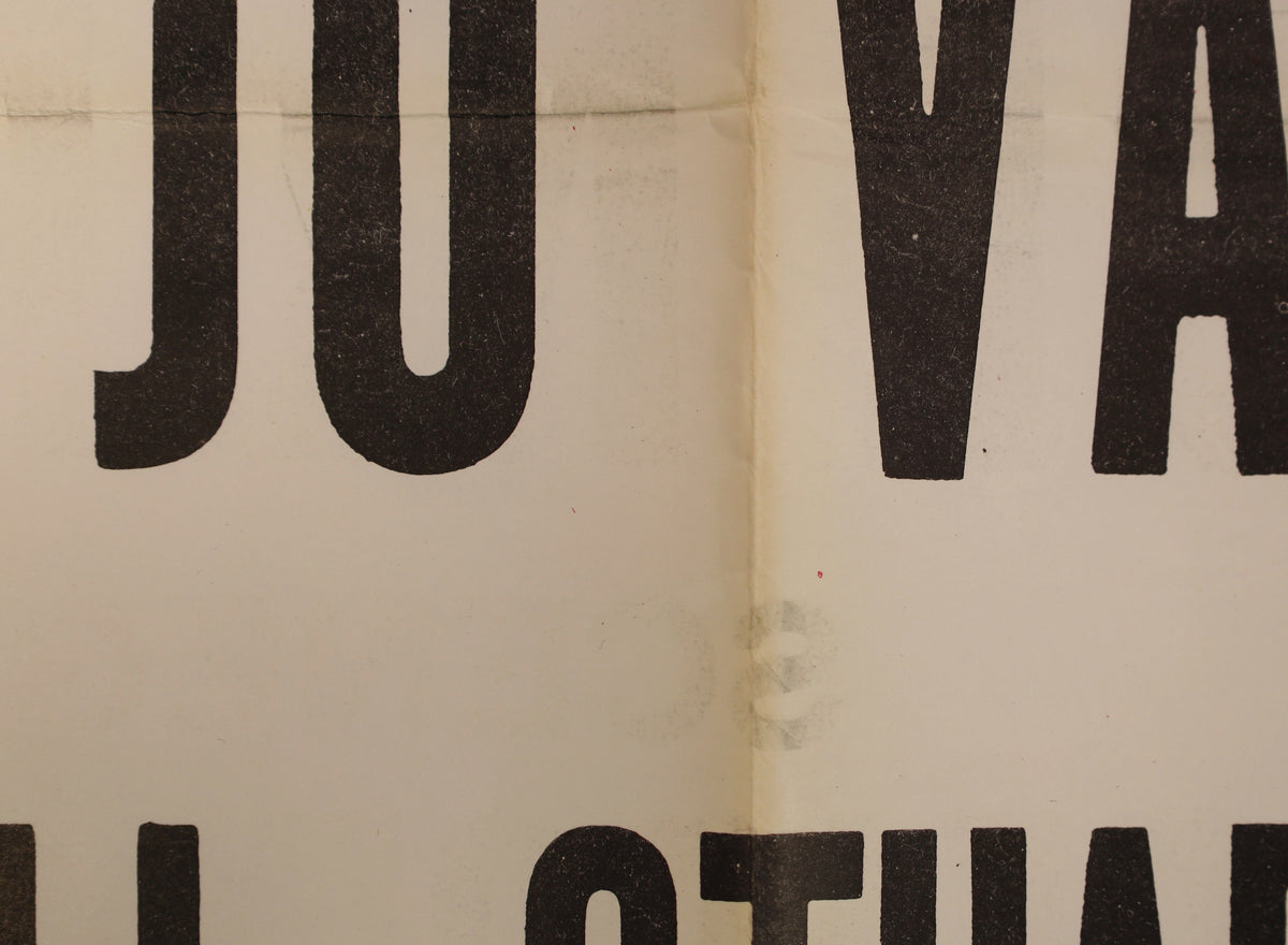 Close-up of the front artwork showing large black lettering, a vertical fold, surface marks, and localized fold wear.