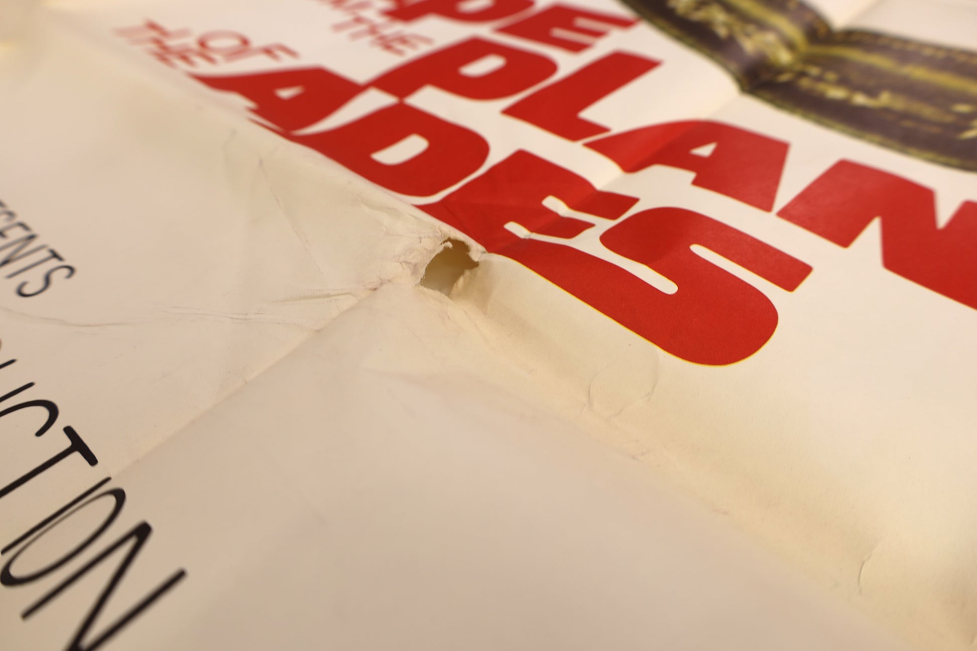 Detail of the Escape from the Planet of the Apes 1971 three sheet poster showing a small area of paper loss and creasing near the red title lettering.