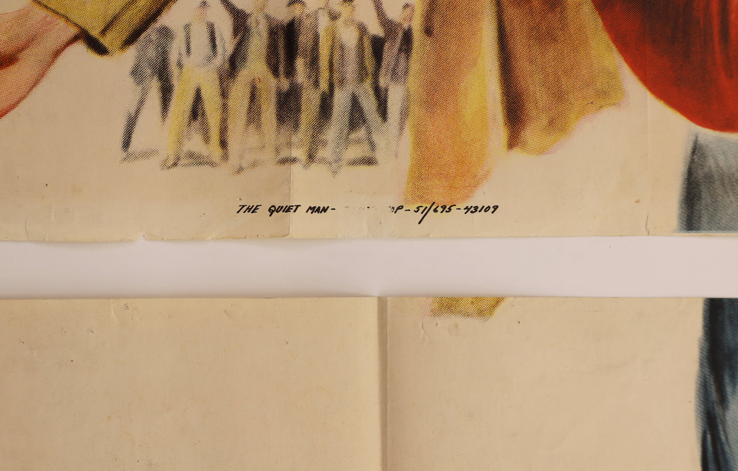 Close-up of a vintage illustrated print or poster showing a group of men in suits, with a handwritten inscription reading 'THE QUIET MAN' and dates below. The print is mounted on a white board, with the lower portion showing aged cream paper.